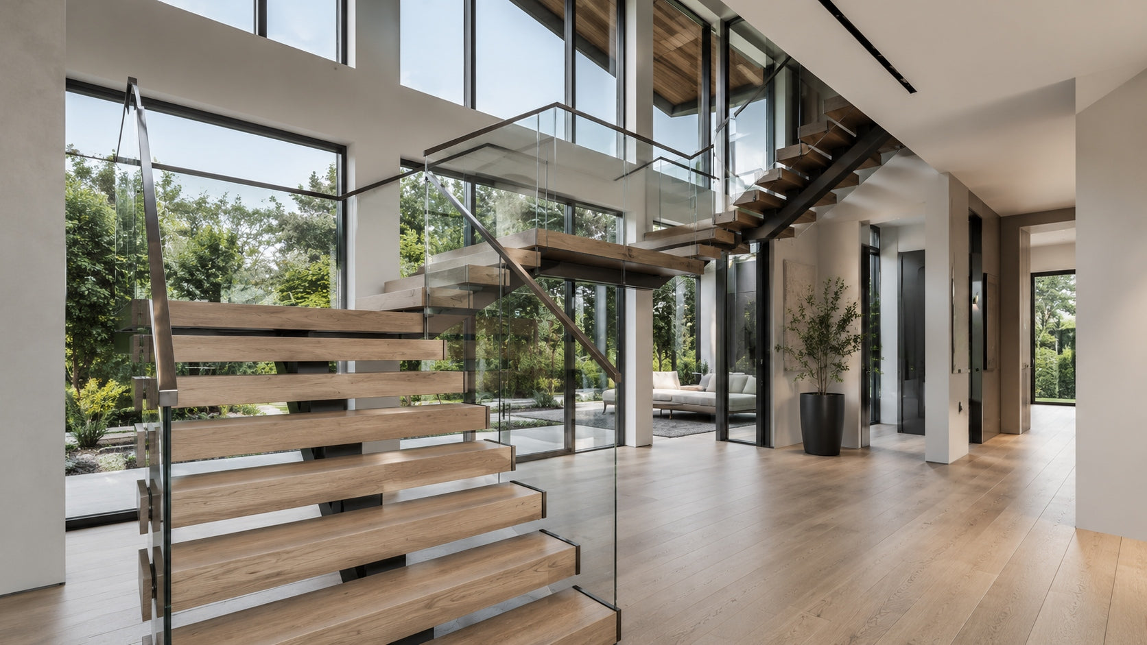 Modern floating stairs with wood treads, black steel stringer, and glass railing in a bright residential interior