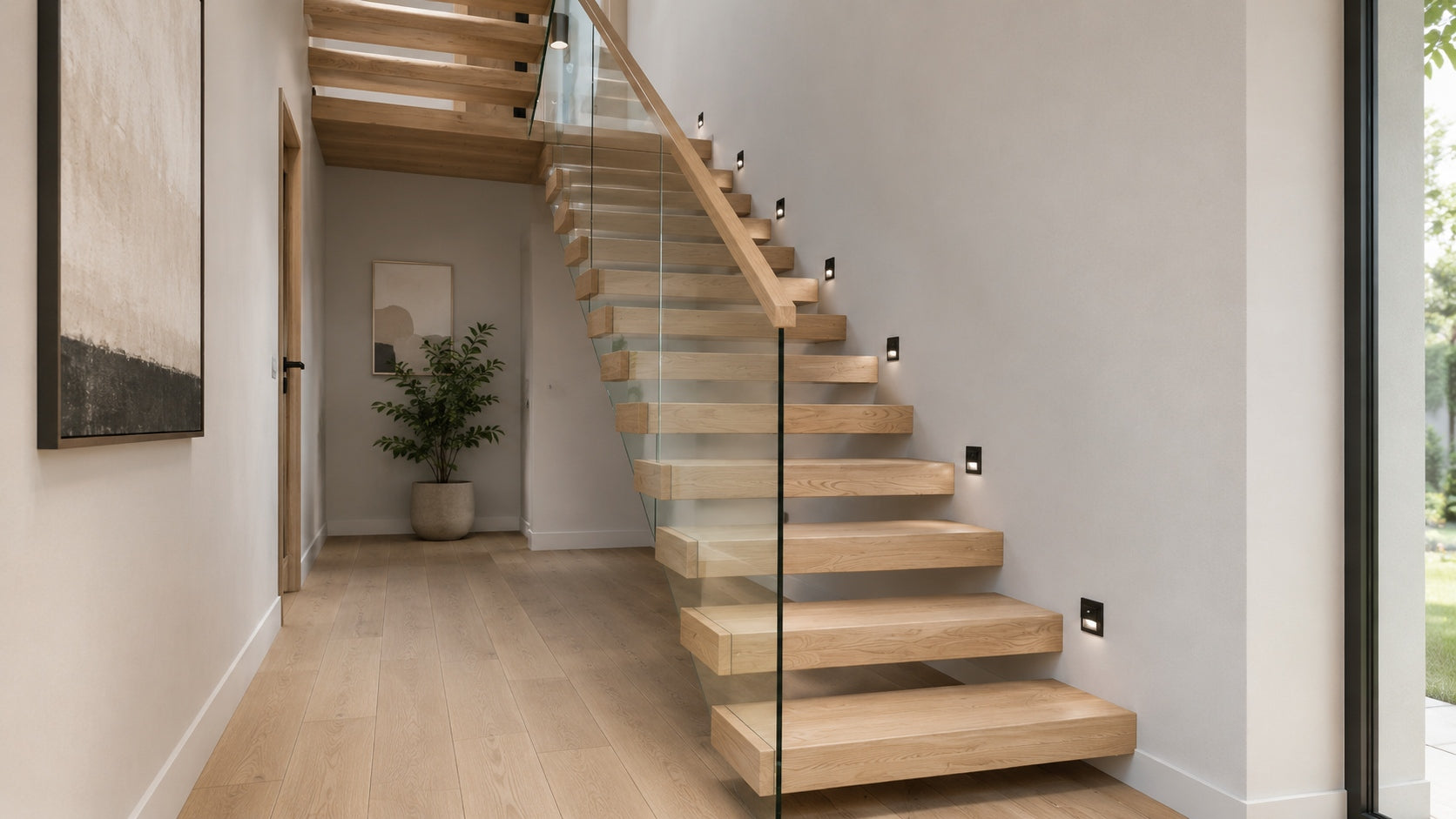 Modern floating staircase with thick white oak stair treads, open risers, matte black steel mono stringer, and glass railing in a bright residential interior