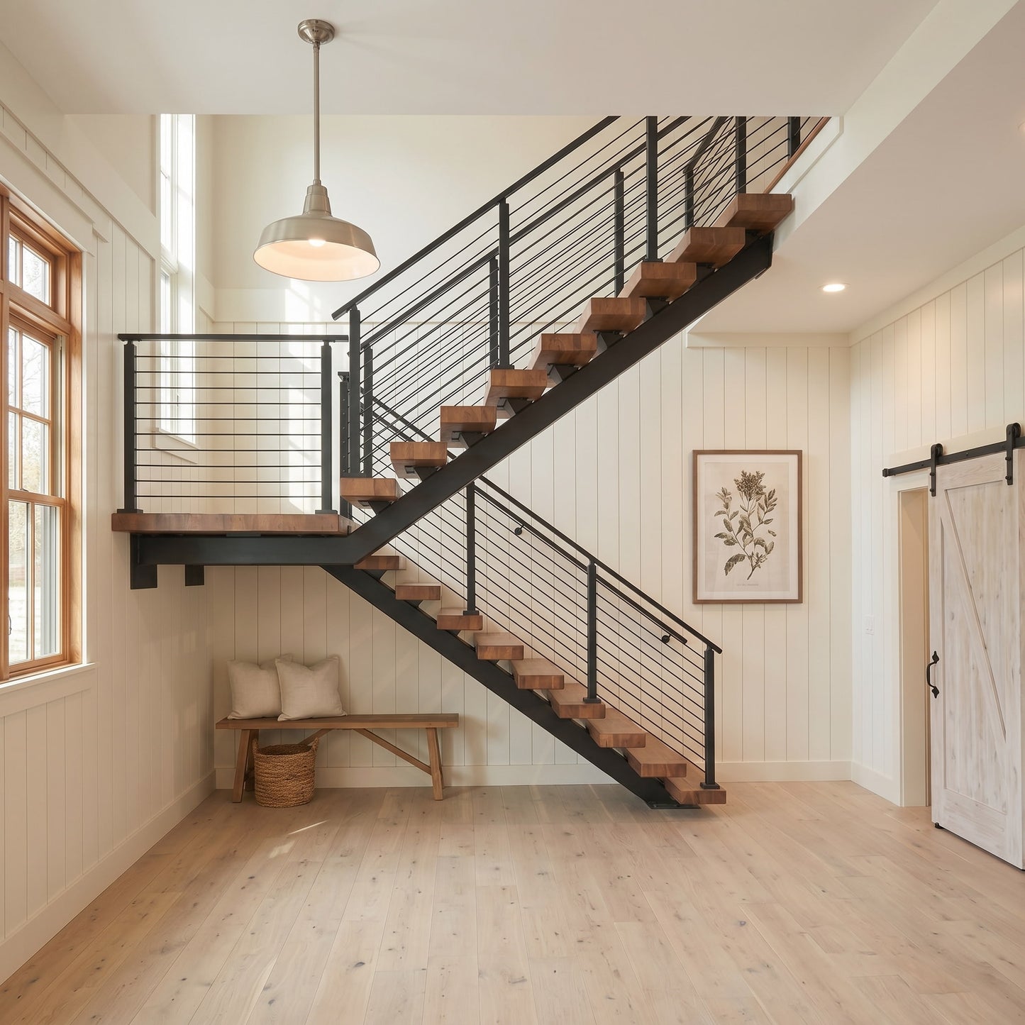 Modern floating stair system with wood treads and black cable railing in a bright residential interior