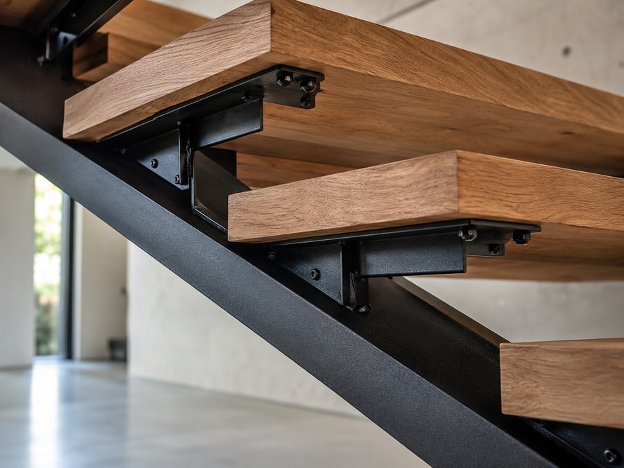 Matte black steel mono stringer support system for floating stairs with welded tread brackets and wood treads.